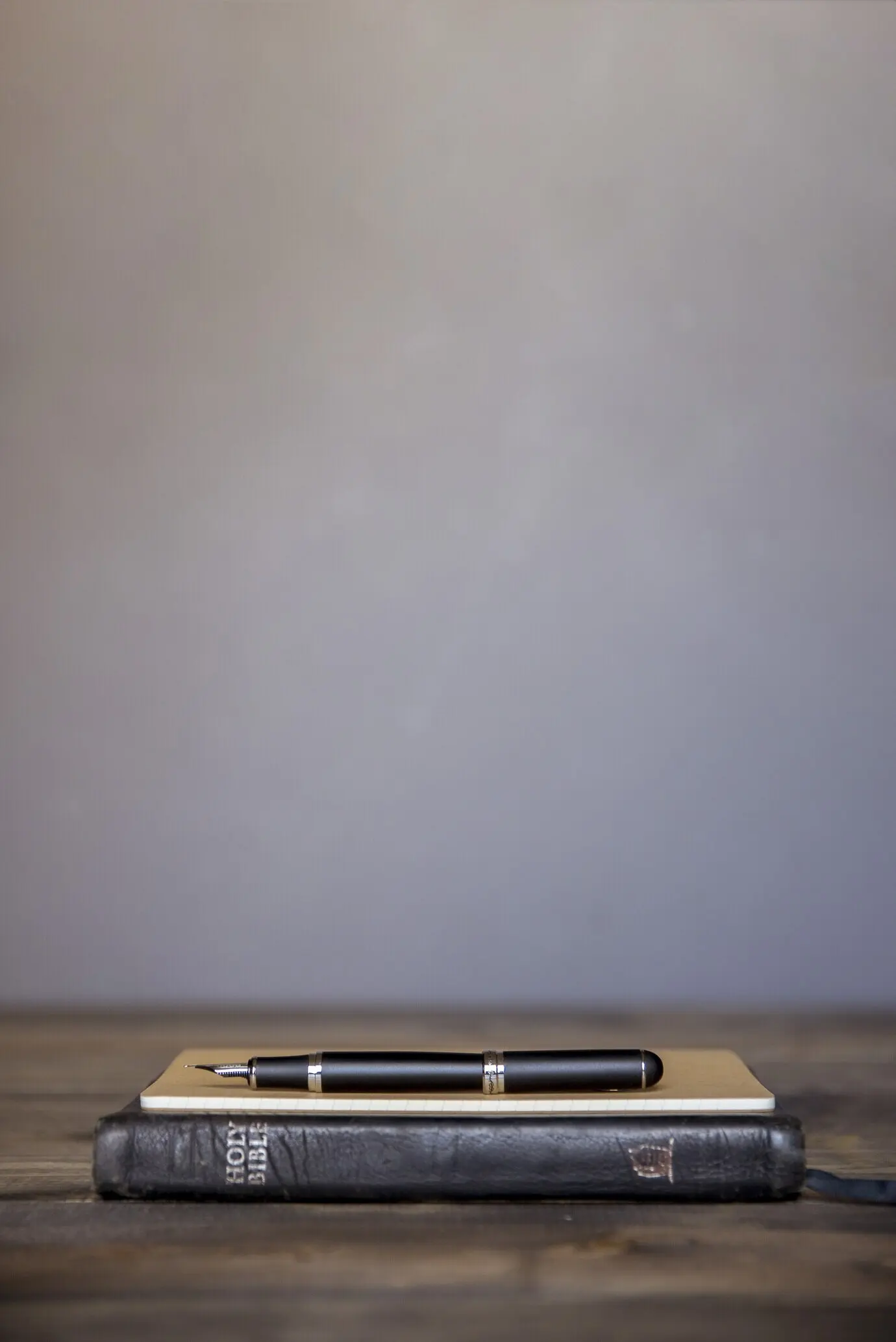 Portrait-oriented photo of a notebook with the fountain pen resting on top on a wooden surface.