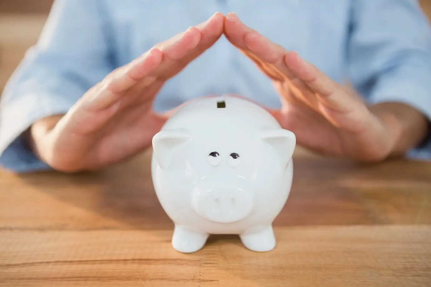 A man performing a roof gesture on a piggy bank